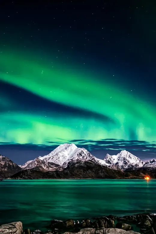 Green aurora over snowy peaks